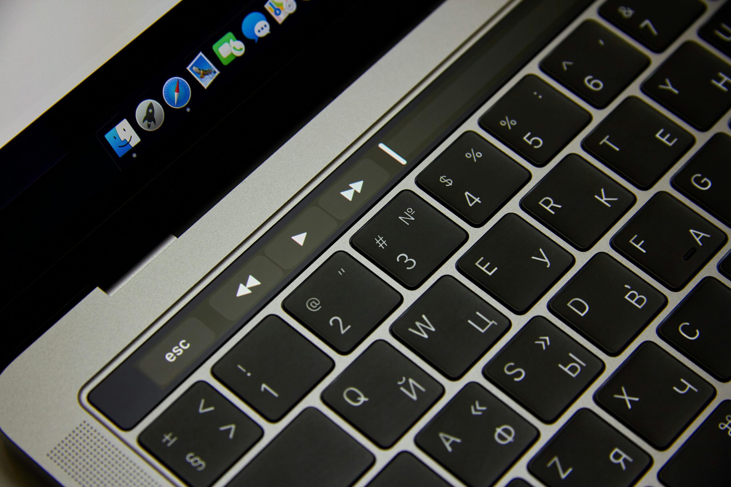 Close-up of a laptop keyboard showcasing Russian letters and a touch bar in a modern setting.